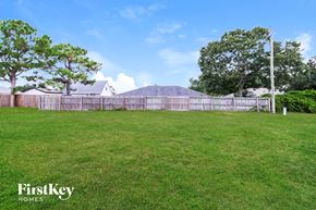 Sebastian house for rent - A grassy field with a fence and trees in the background.