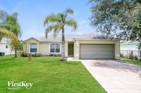 Kissimmee house for rent - a beige house with palm trees on the lawn and a driveway
