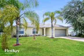Kissimmee house for rent - a home with two palm trees in front of it