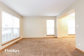 Huntley house for rent - a spacious living room with two windows and carpeting