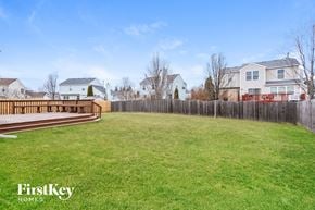Huntley house for rent - a backyard with a deck and a grassy lawn and a fence