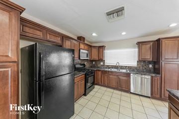 Peoria house for rent - A black refrigerator in a kitchen with wooden cabinets.