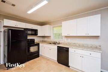 Covington house for rent - a kitchen with white cabinets and black appliances