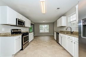 Hampton house for rent - an empty kitchen with white cabinets and stainless steel appliances