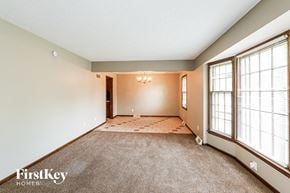 Kansas City house for rent - A spacious room with a carpeted floor and a window with blinds.
