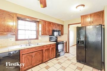 Kansas City house for rent - A kitchen with wooden cabinets and a black refrigerator.