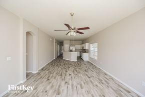 Gibsonton house for rent - A spacious room with a fan and wooden flooring.