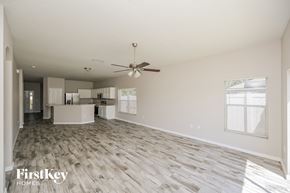 Gibsonton house for rent - A spacious room with a fan and wooden flooring.