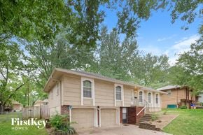 Kansas City house for rent - A house with a garage is surrounded by trees.