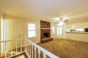 Kansas City house for rent - A spacious living room with a fireplace and a carpeted floor.