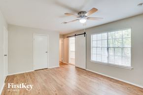 Spring house for rent - A spacious room with a ceiling fan and sliding glass doors leading to a balcony.