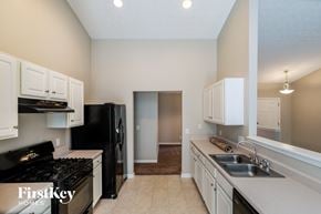Lawrenceville house for rent - a kitchen with white cabinets and a black stove and a sink