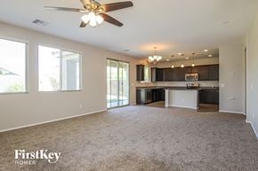 Peoria house for rent - A spacious living room with a ceiling fan and a kitchen area in the background.