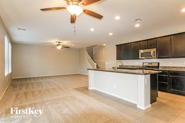 Peoria house for rent - A spacious kitchen and living room with a ceiling fan and lighting fixtures.