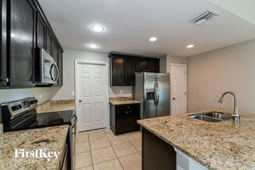 Cape Coral house for rent - a kitchen with granite counter tops and a stainless steel refrigerator