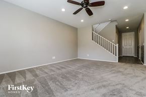 Peoria house for rent - an empty living room with a ceiling fan and a staircase