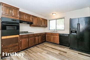 Florissant house for rent - A kitchen with wooden cabinets and black appliances.