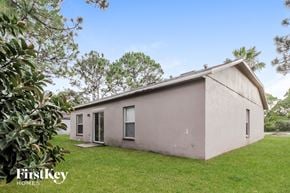 Sebastian house for rent - A house with a grassy lawn and trees in the background.