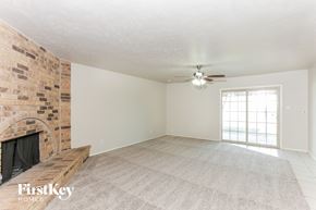 Grand Prairie house for rent - an empty living room with a brick fireplace and a ceiling fan