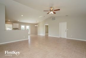 Port Charlotte house for rent - an empty living room with a ceiling fan and a kitchen