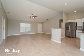 Port Charlotte house for rent - an empty kitchen and living room with a ceiling fan