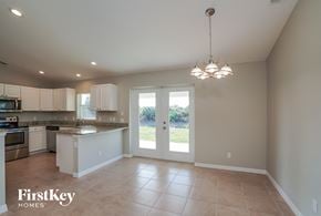 Port Charlotte house for rent - an empty kitchen with white cabinets and a door to a yard
