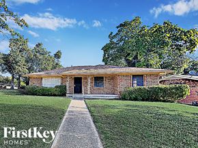 Dallas house for rent - the front of a brick house with a lawn and a sidewalk