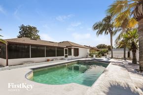 Orlando house for rent - A pool in a backyard with a house and palm trees.