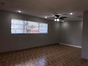 Hollywood house for rent - an empty living room with a ceiling fan and a window