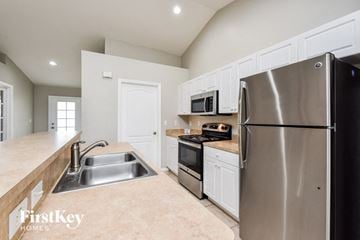 Cape Coral house for rent - a kitchen with stainless steel appliances and white cabinets