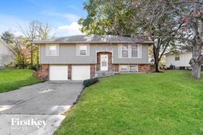 Lee's Summit house for rent - a gray house with white garage doors and a green lawn