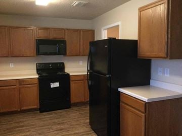 Cedar Hill house for rent - a kitchen with black appliances and wooden cabinets