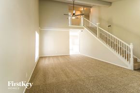 Missouri City house for rent - A spacious room with a staircase and a ceiling fan.