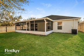 Riverview house for rent - A house with a white exterior and a black roof is surrounded by a fence and has a grassy yard.