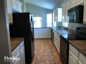 Crowley house for rent - a large kitchen with white cabinets and black appliances