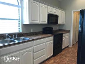 Crowley house for rent - a kitchen with white cabinets and a black refrigerator