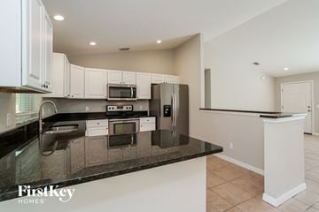 Port Charlotte house for rent - a kitchen with black granite counter tops and white cabinets
