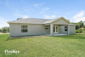 Port Charlotte house for rent - a small white house with a grassy yard and a porch