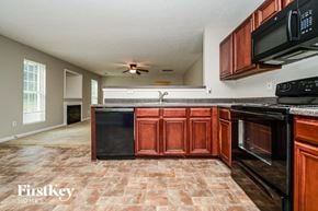 Covington house for rent - a kitchen with black appliances and wooden cabinets