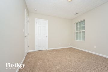 Covington house for rent - a spacious living room with beige carpet and a white door