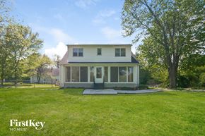 Saint Louis house for rent - the back of a white house with a lawn and a yard with trees