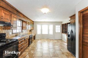 Kansas City house for rent - A kitchen with a black stove top oven and a black refrigerator.