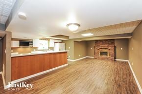 Kansas City house for rent - A spacious living room with wood flooring and a brick fireplace.