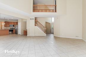 Batavia house for rent - A spacious living room with a kitchen in the background and a staircase leading to the upper floor.