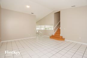 Miami house for rent - A spacious room with a staircase leading to another room.