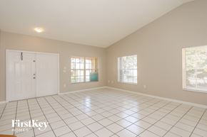 Miami house for rent - A spacious room with a white tile floor and a large window.