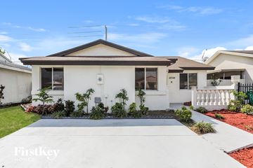 Miami house for rent - a white house with a driveway and a white picket fence