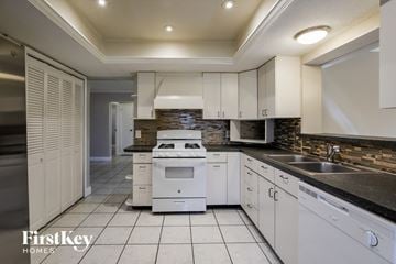 Sunrise house for rent - a kitchen with white appliances and white cabinets