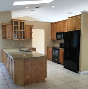 Wellington house for rent - A kitchen with wooden cabinets and a granite countertop.