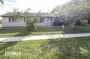 Wellington house for rent - a small white house with a lawn and trees
